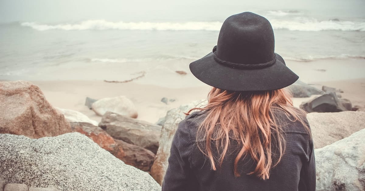 woman in california wearing a hat looking out at beach after divorcing from ten year marriage