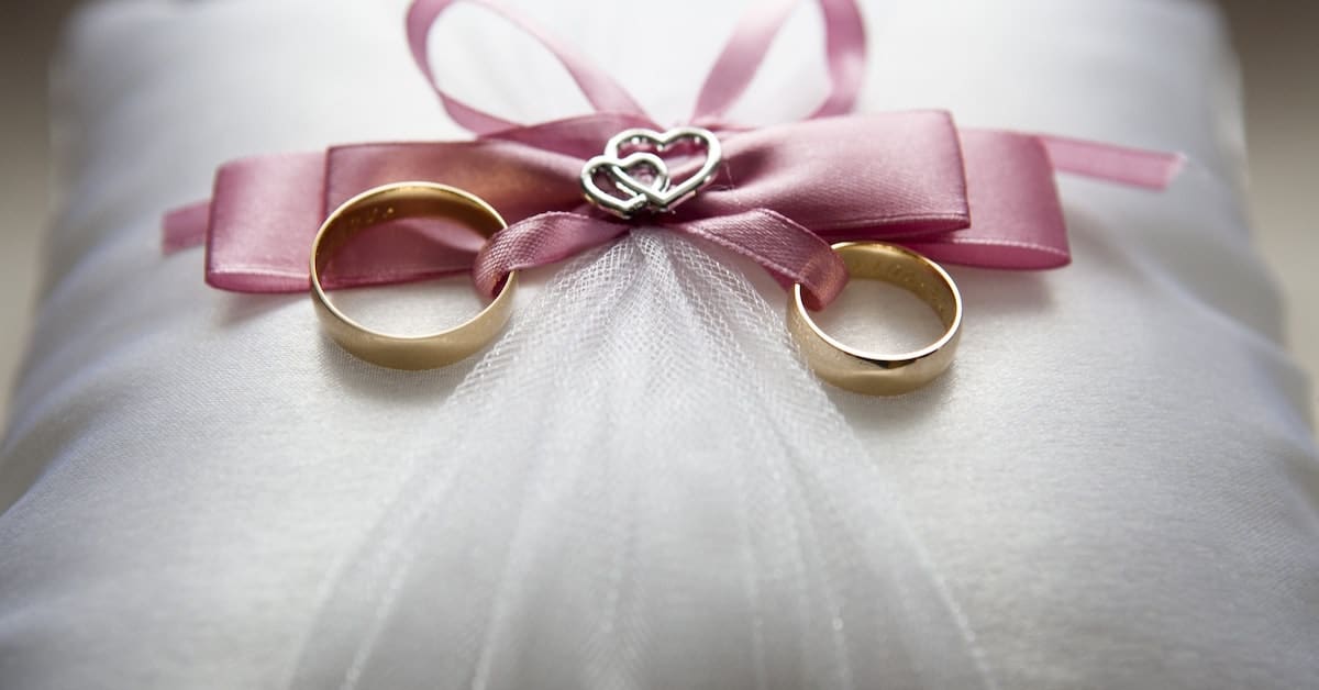 wedding rings on a pillow with pink ribbon in texas marriage