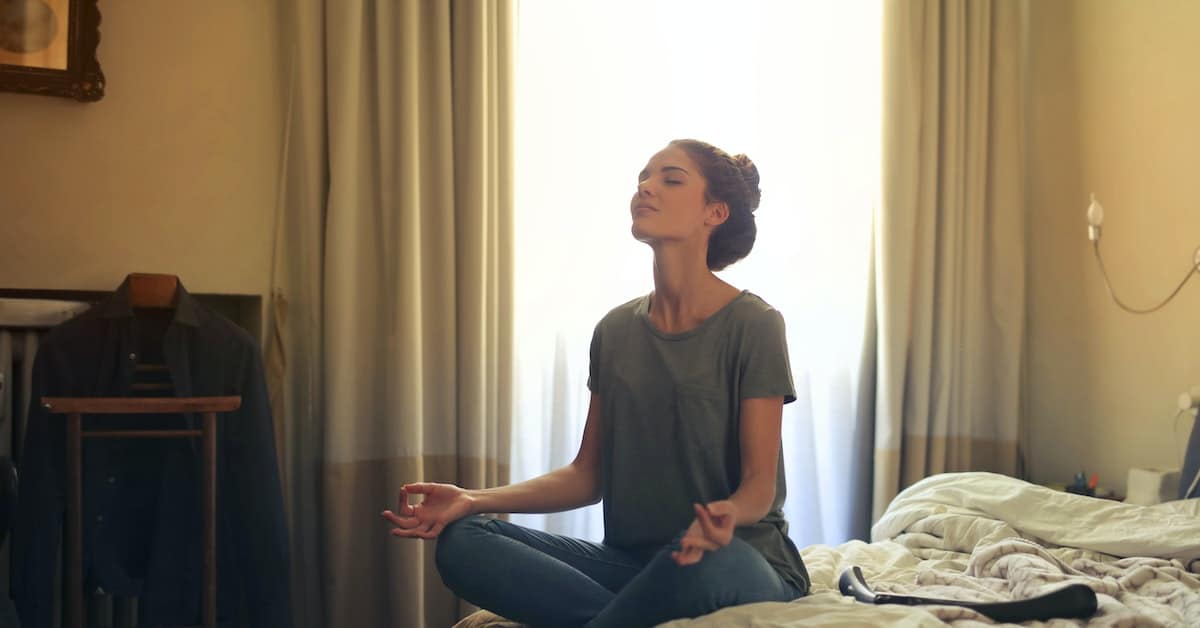 woman sitting on bed meditating to maintain mental health during texas amicable divorce