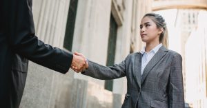 woman in suit shaking hands with man outside courthouse in amicable divorce