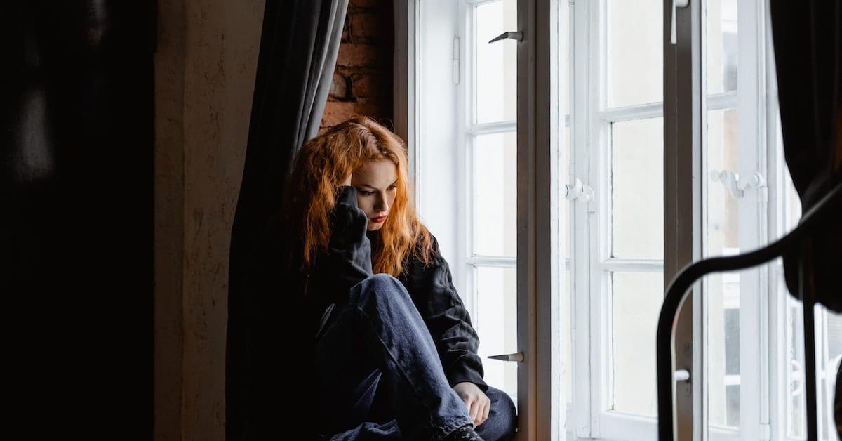 woman on windowsill sad thinking about separation vs divorce in texas