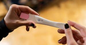 positive pregnancy test held by woman getting divorce in texas