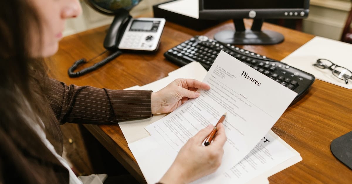 person signing divorce paperwork with lawyer representing both parties