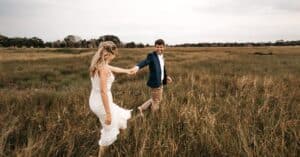 couple with an informal marriage in texas holding hands walking through a field